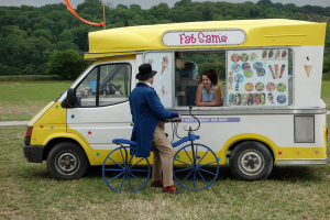 One of Fat Sam's Ice Cream Vans at a history festival in Wiltshire, with a customer a bicycle in period costume buying an ice cream.