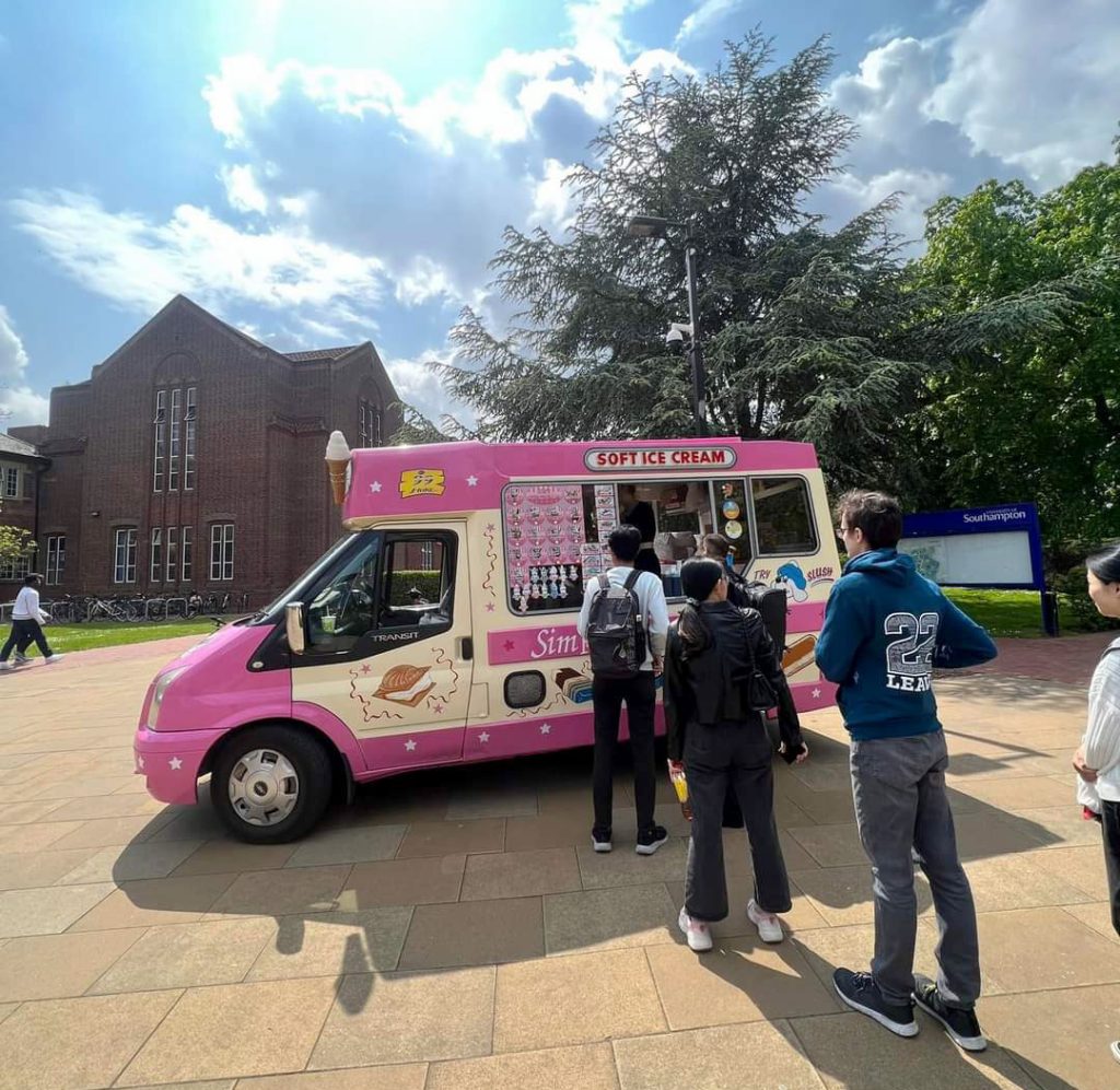 Fat Sam's Pink Ice cream van parked outside Southampton university with 3 students in a queue waiting to be served their free ice cream