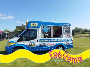 A classic blue and white Fat Sam's ice cream van parked on a grass field under a clear blue sky.